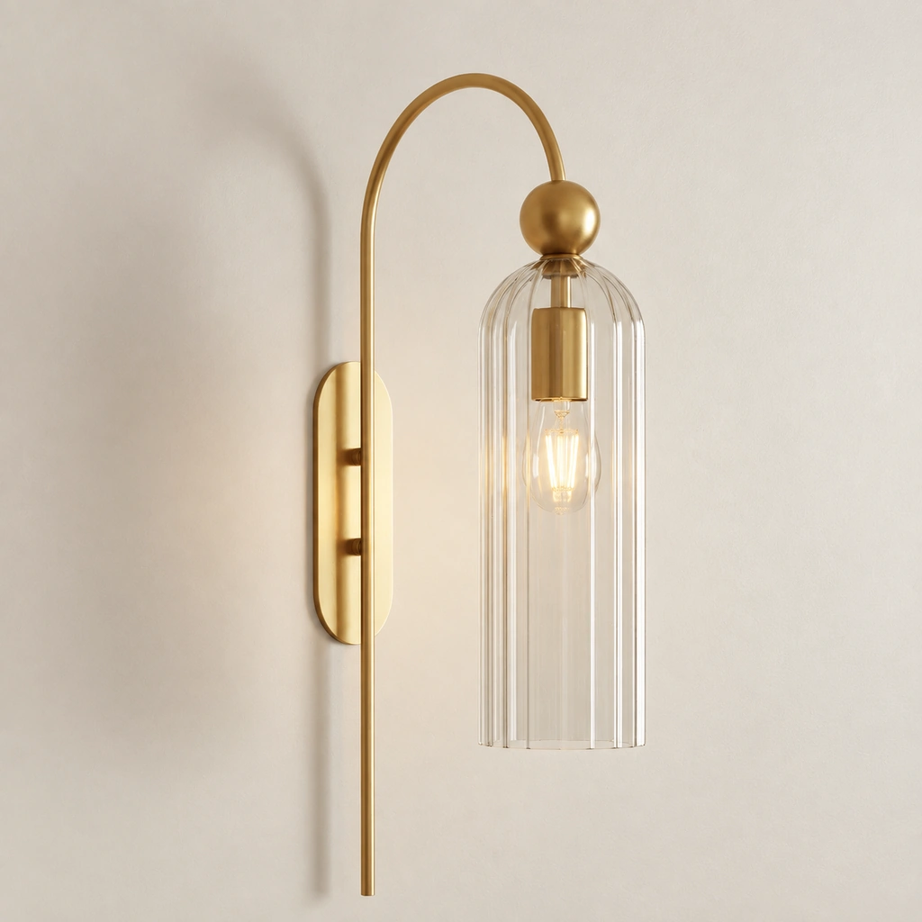 Full view of the Azura clear-glass sconce: ribbed shade, gold arched arm, ball joint, socket and wall plate against a pale wall