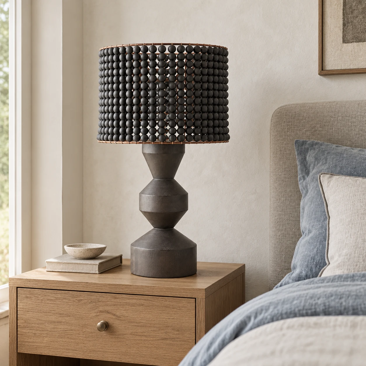 Dark wood beaded table lamp beside a bed