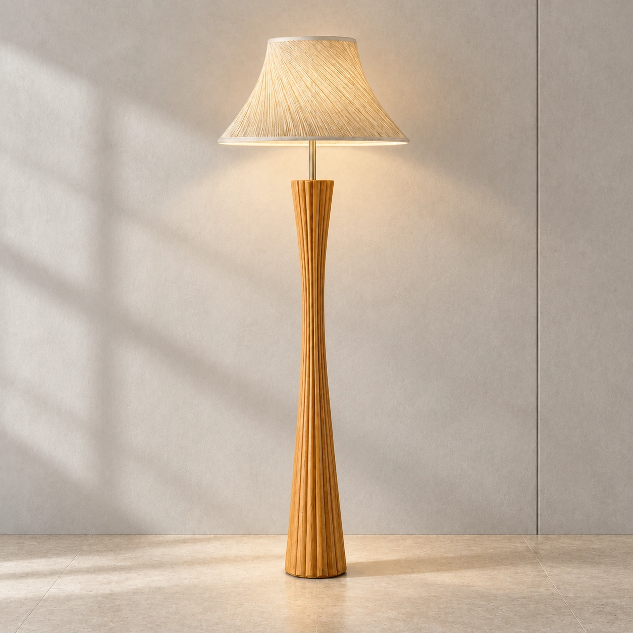 Elodie carved wood floor lamp illuminated against a restrained mineral wall