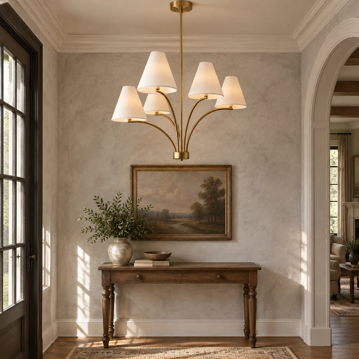 Warm brass fabric shade branch chandelier installed over an entry console