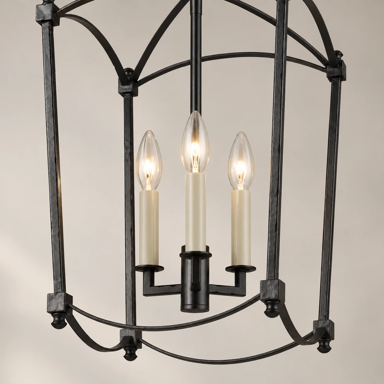 Close view of the Mabel chandelier's three candle-style sockets and clear flame bulbs