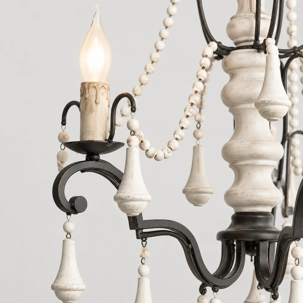 Close detail of a black iron scroll arm, candle-style socket and carved wood bead