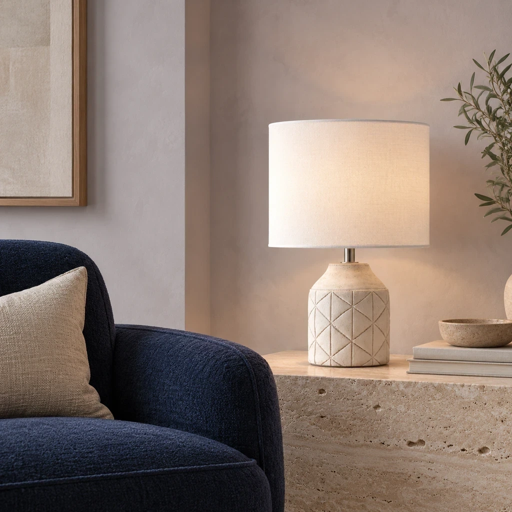 Merritt Geometric Carved Wood Table Lamp with White Drum Shade on a travertine reading ledge