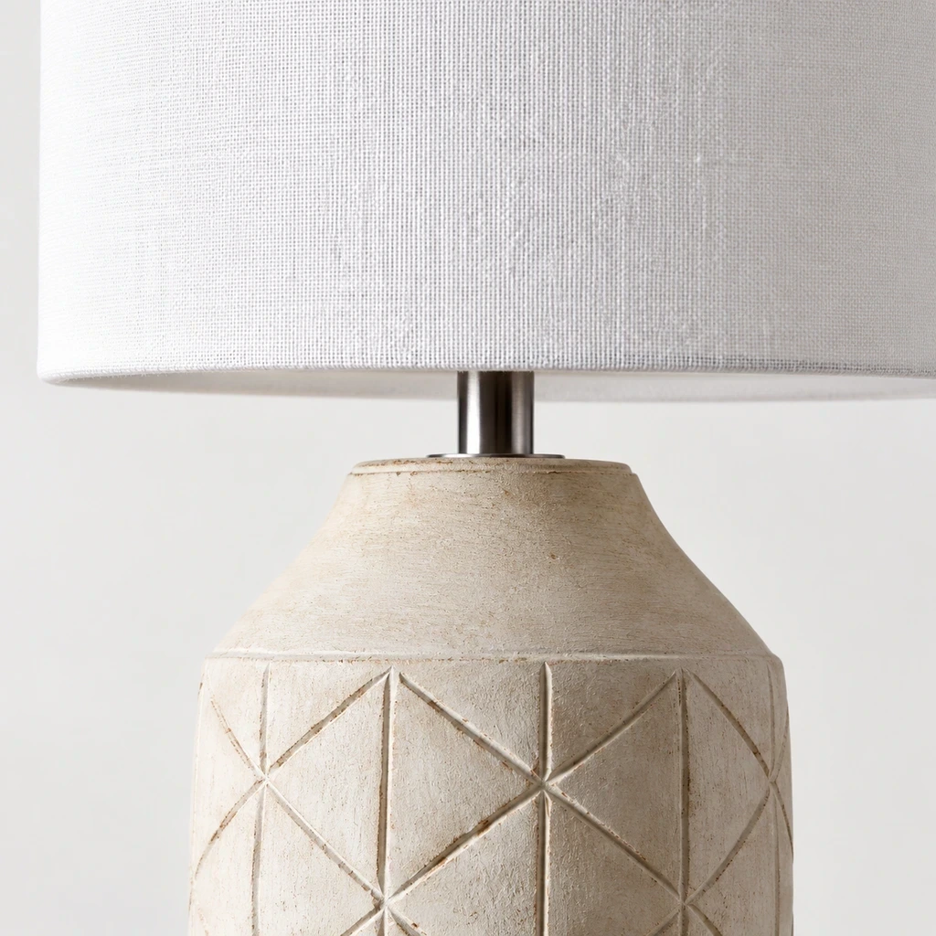 Close detail of the white fabric shade, wood neck and patterned lamp body