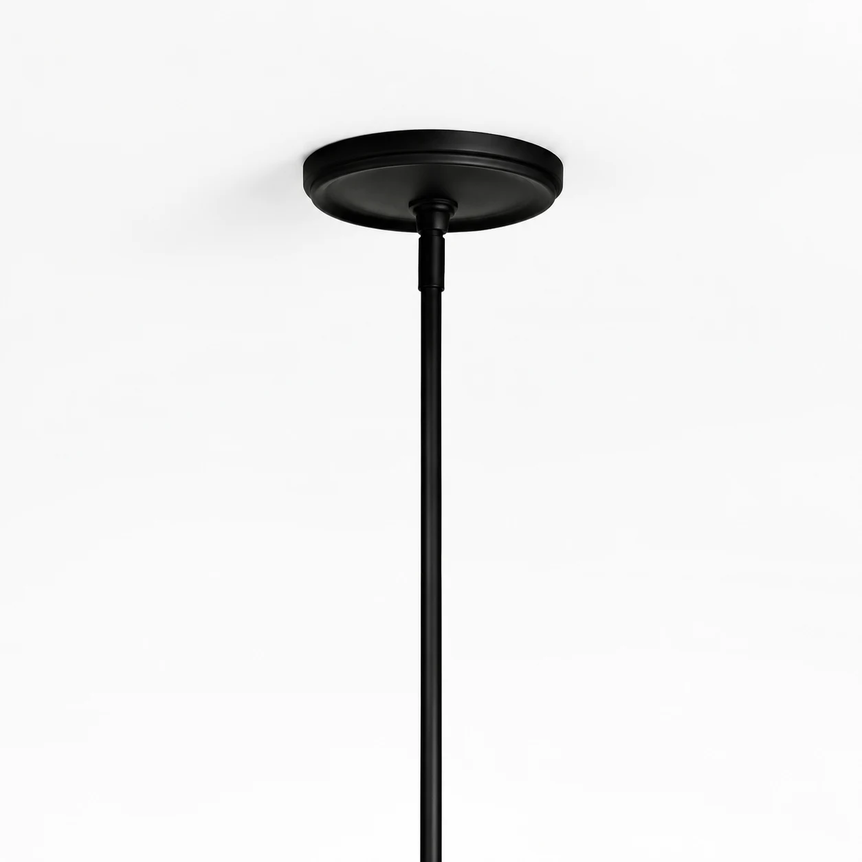 Close view of the shallow black ceiling canopy and slim vertical suspension rod