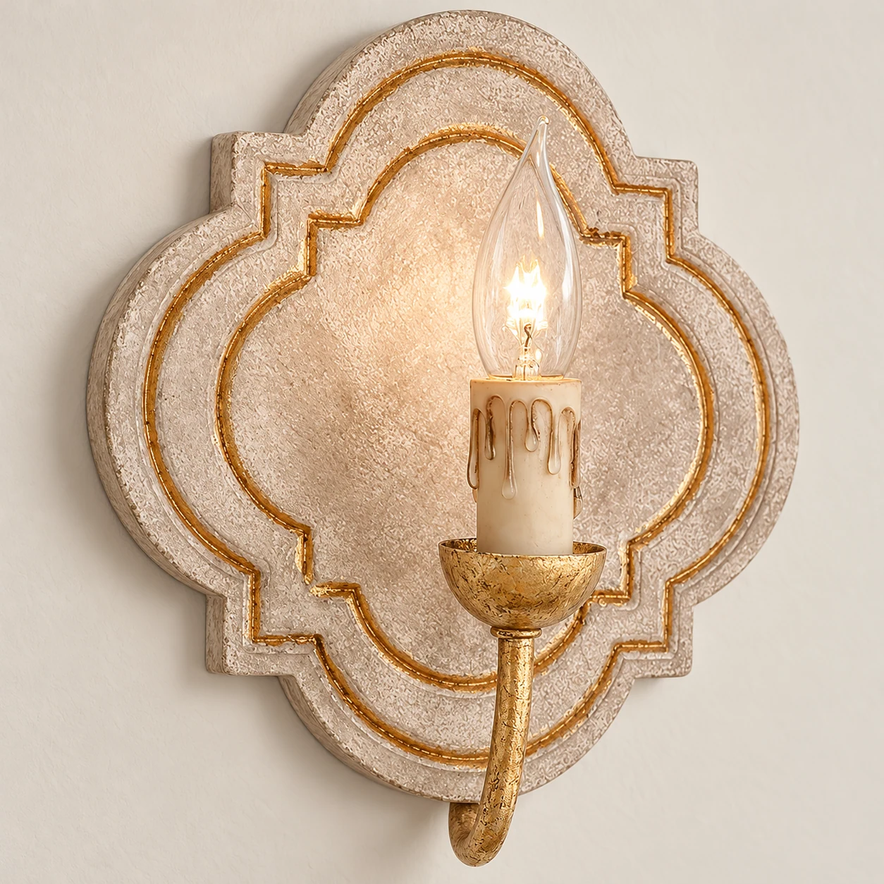 Close detail of the gold candle arm and wax-drip sleeve on the Nola wall sconce
