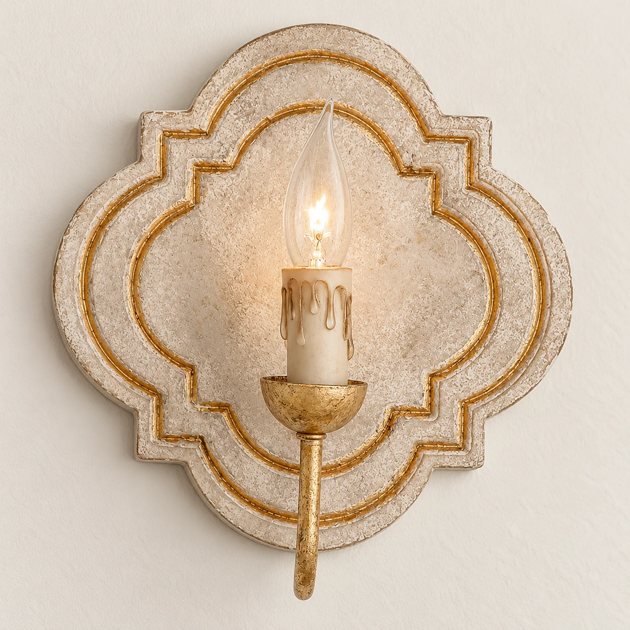 Close detail of the carved cream wood quatrefoil backplate on the Nola wall sconce