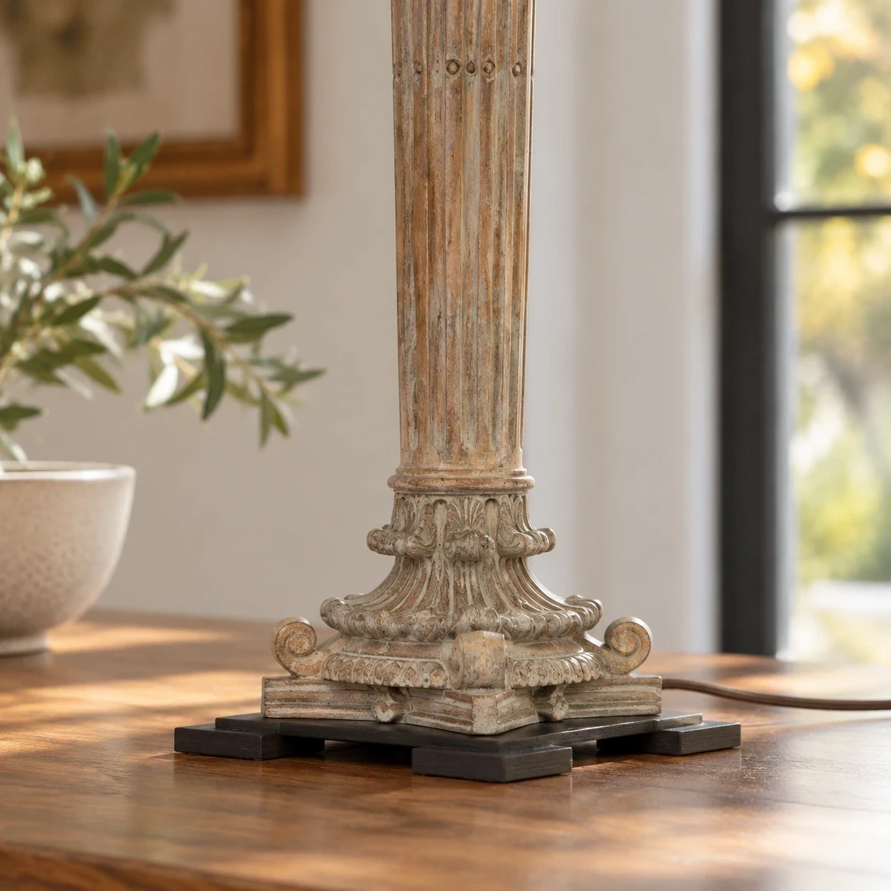 Detalle cercano de la talla ornamental inferior y la base cuadrada oscura sobre una mesa.
