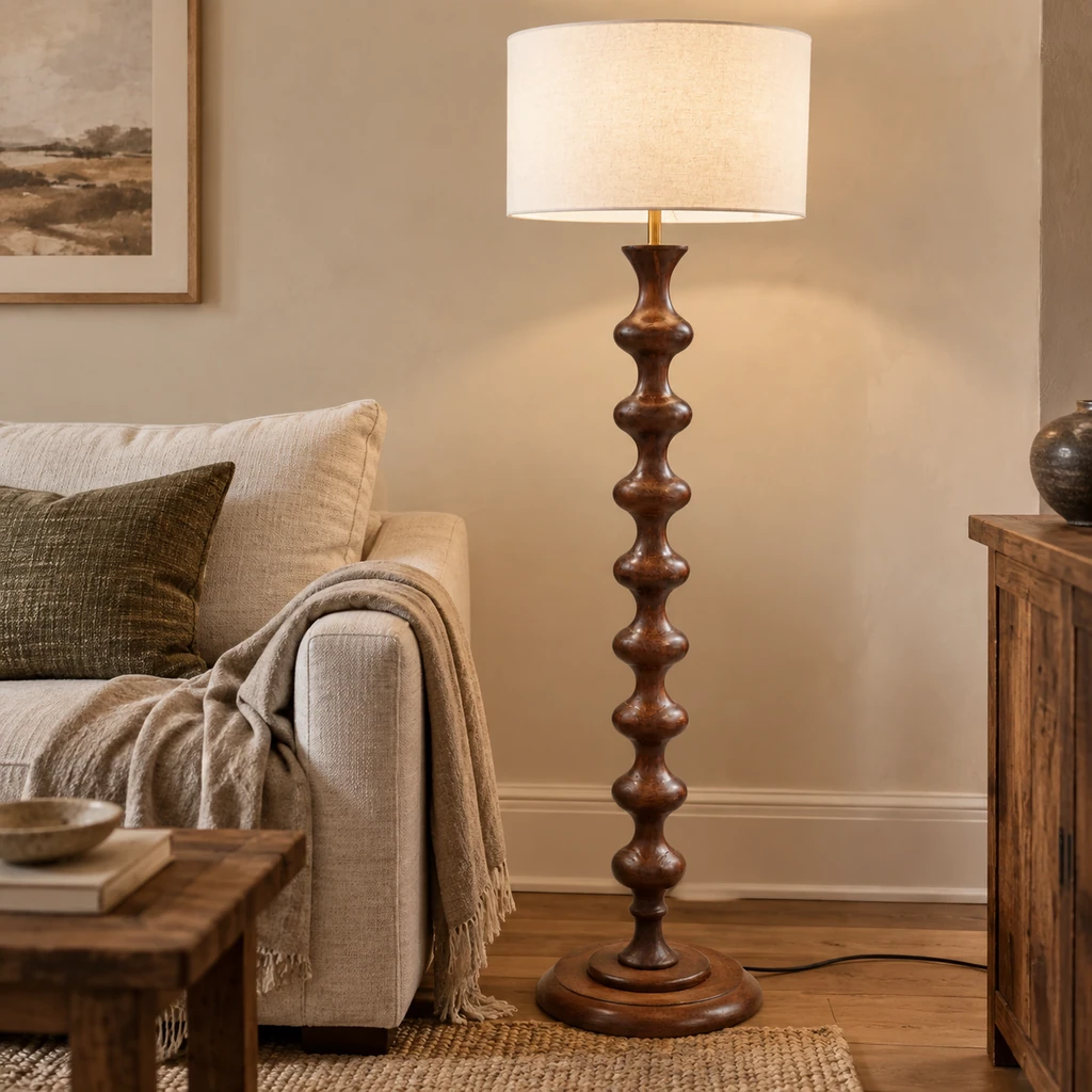 Lampadaire Avery en bois sculpté couleur noyer à côté d'un canapé couleur avoine