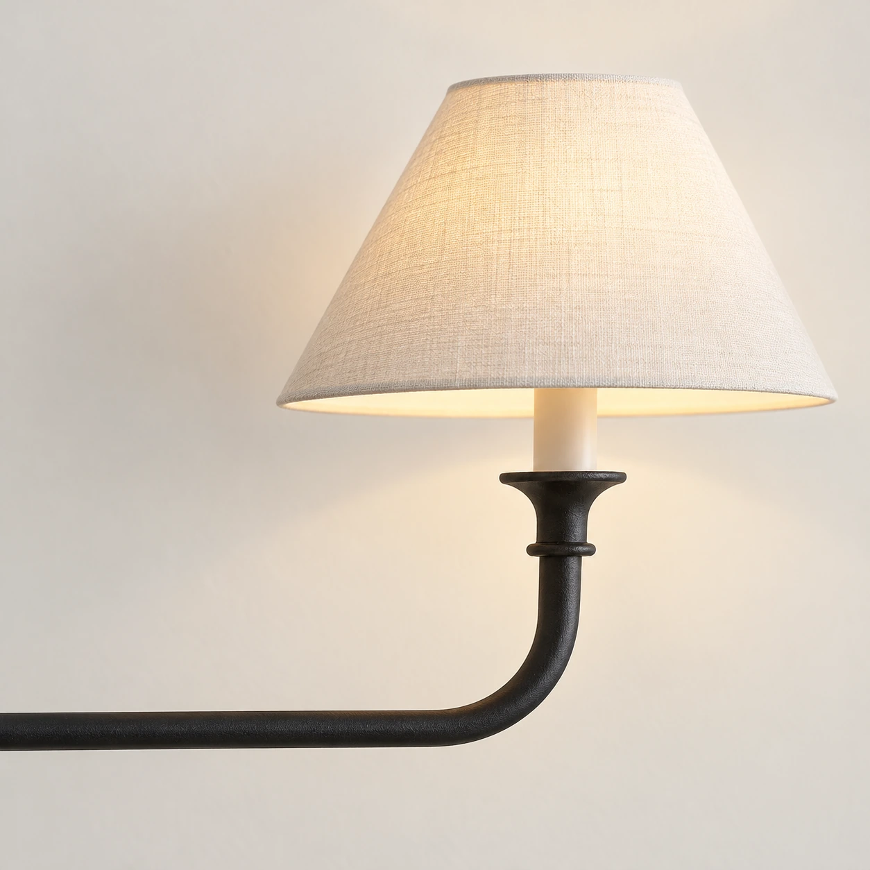 Close detail of the ivory fabric shade and curved black iron arm