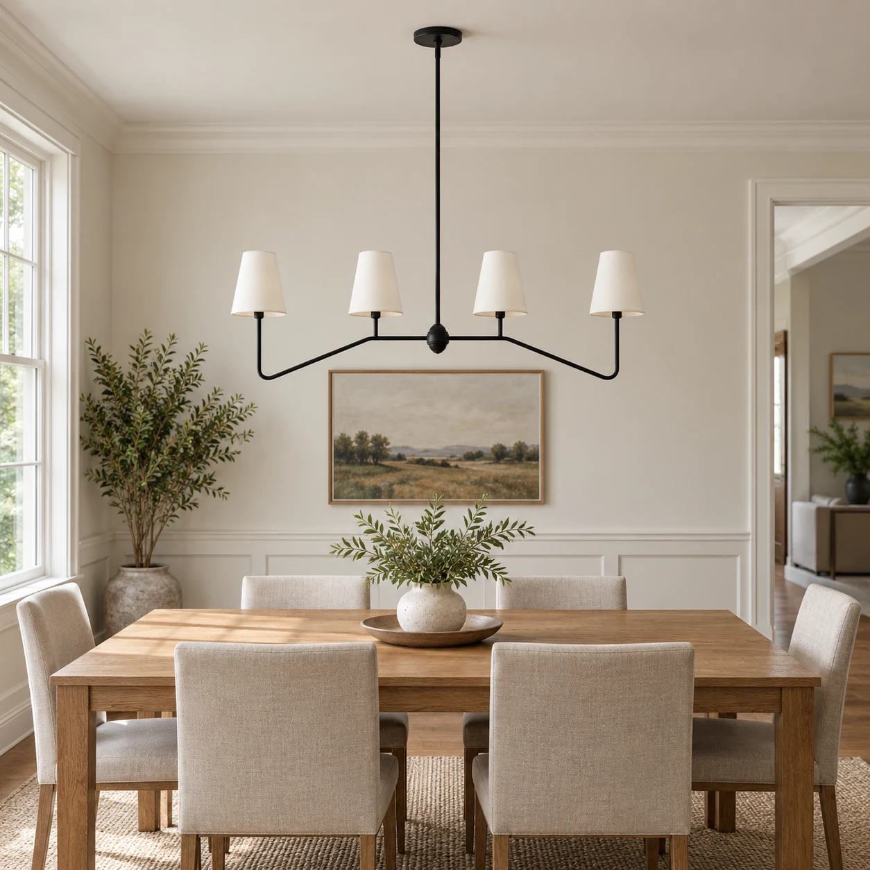 Lámpara de araña de hierro con cuatro luces y pantalla blanca sobre una mesa de comedor de roble en una casa estadounidense.