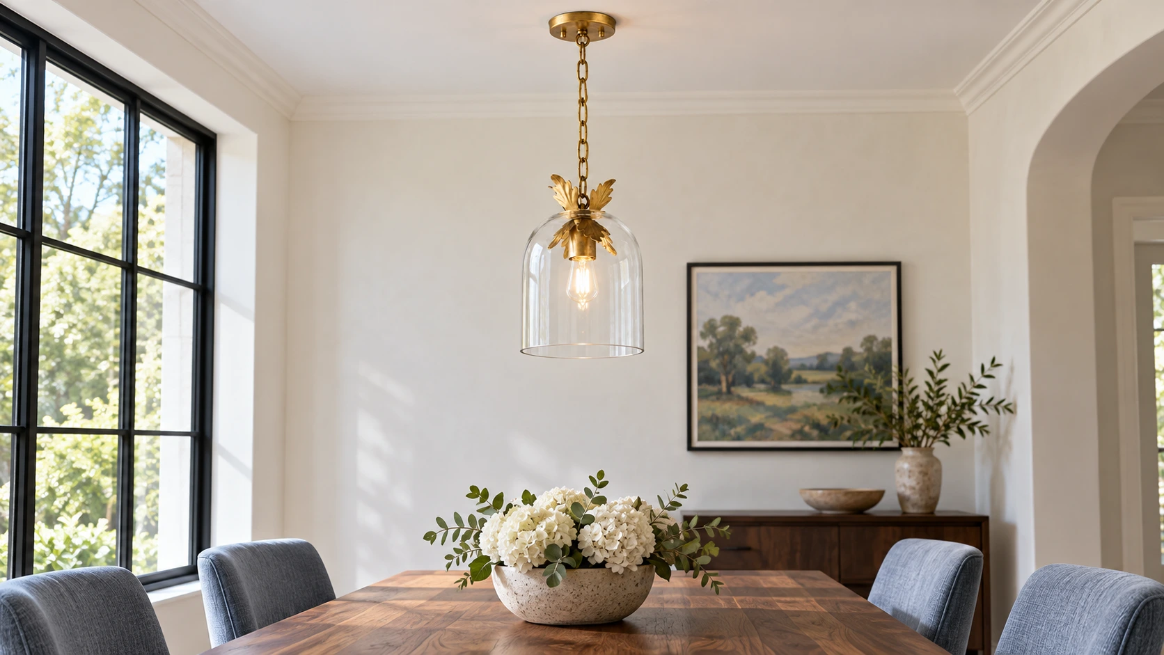 Lámpara colgante de cristal transparente con detalles en pan de oro antiguo en un comedor.